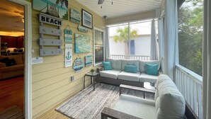 A cozy living room with a sofa, a ceiling fan, and various wall decorations. -  PARADISE PALMS 6016 at Rookery III - Walk to Beach - Relax by Pools (Gulf Shores)