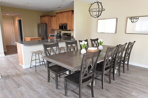 A modern kitchen with wooden cabinets, a central island, and a dining area with a dark wooden table and chairs. - Spacious townhouse 4 miles from the beach (Selbyville)