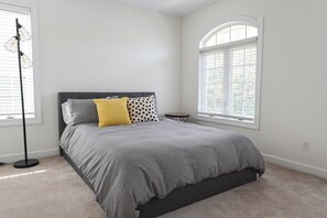A bedroom with a bed, a floor lamp, a small table, and a window. - Spacious townhouse 4 miles from the beach (Selbyville)