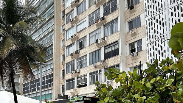 Een meerlaags gebouw met balkons, airconditioners en een palmboom.