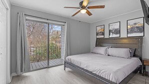 Et soveværelse med seng, ventilator, balkon med udsigt og tre billeder hængende på væggen.