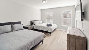 Et soveværelse med to senge, et natbord, et træskab og en loftslampe.
