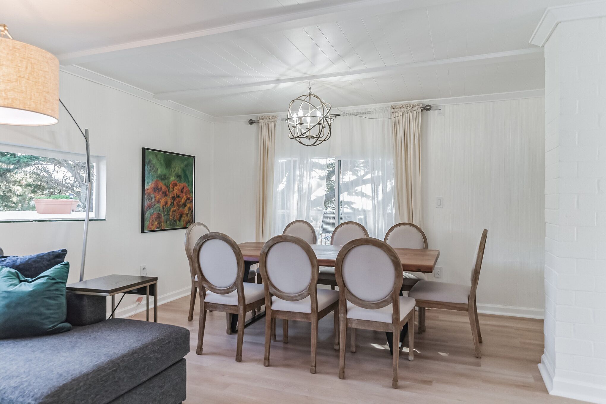 Een eetgedeelte met een houten tafel en stoelen, een kroonluchter en een schilderij aan de muur.