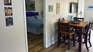 Una habitación con cama, una mesa de comedor con sillas, televisión y obras de arte en las paredes.