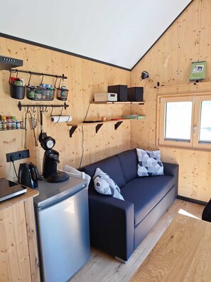 A compact room with a kitchenette, a sofa, and a window.