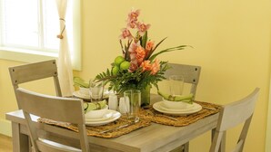 A dining table set with chairs, a vase of flowers, and a decorative piece on the wall. - Cozy accommodations in a great location. (Cruz Bay)