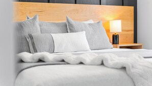 A neatly made bed with a wooden headboard, multiple pillows, and a bedside lamp.