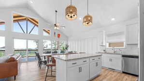 A spacious kitchen with white cabinetry, a large island, and a dining area with a view.