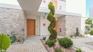 A building entrance with a stone facade, a wooden door, a spiral garden feature, and a paved walkway. - Bodrum Local House (Bodrum)