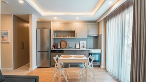 A modern kitchen with a dining area, built-in appliances, and a large window with curtains. - Bodrum Local House (Bodrum)
