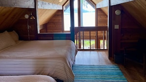 Un dormitorio acogedor en el ático con una cama grande, vigas de madera y vistas al exterior.