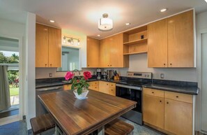 Una cocina moderna con armarios de madera, una isla central con un florero y un comedor.