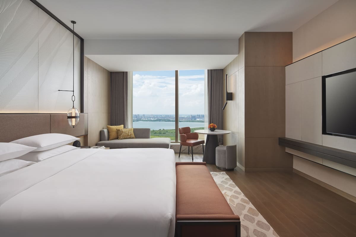 Une chambre d’hôtel moderne avec un grand lit, un bureau et une vue sur la ville.