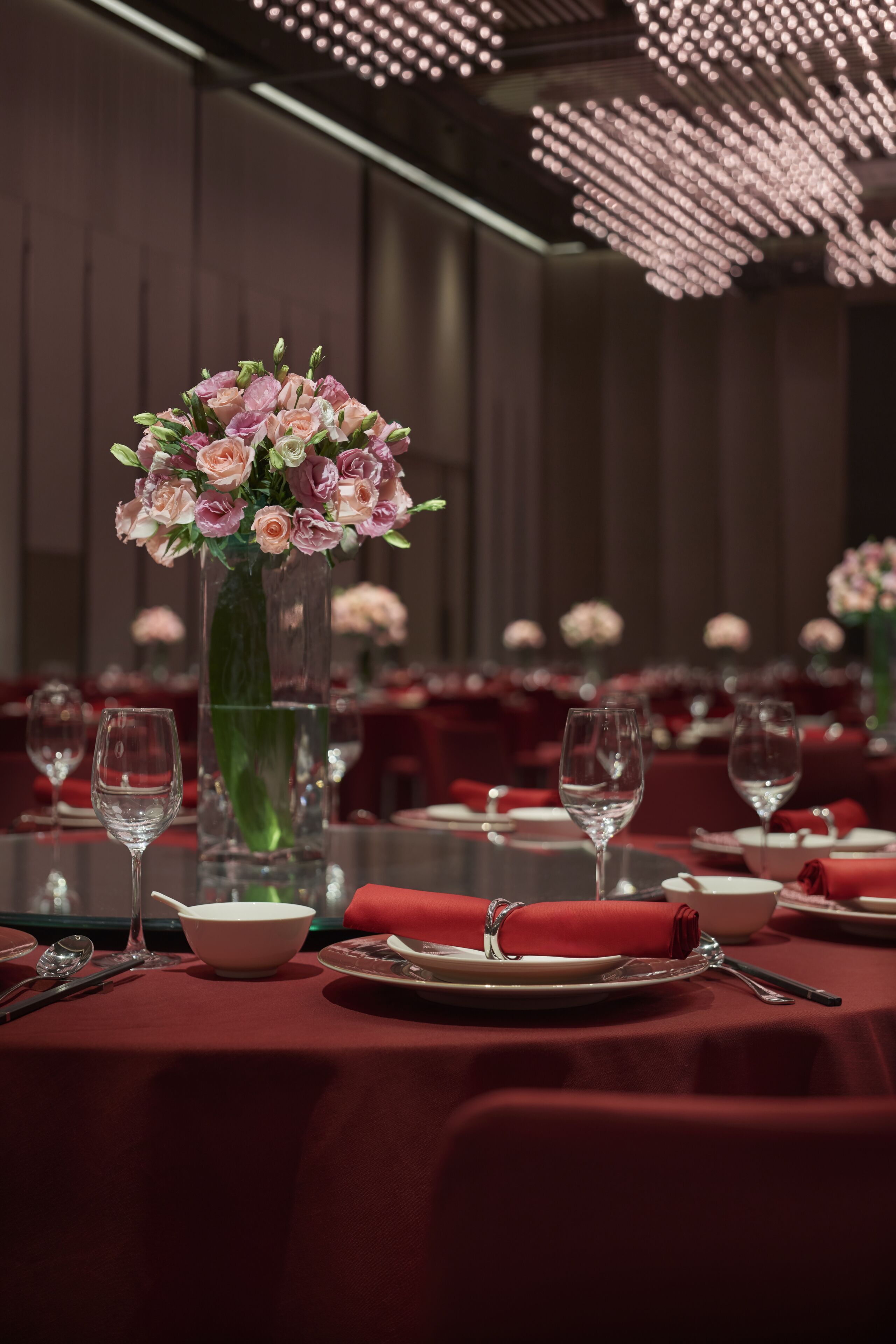 A dining table set with red tablecloths, white plates, and clear stemware.