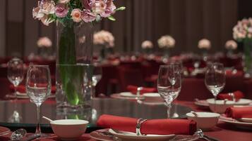 A dining table set with red tablecloths, white plates, and clear stemware.