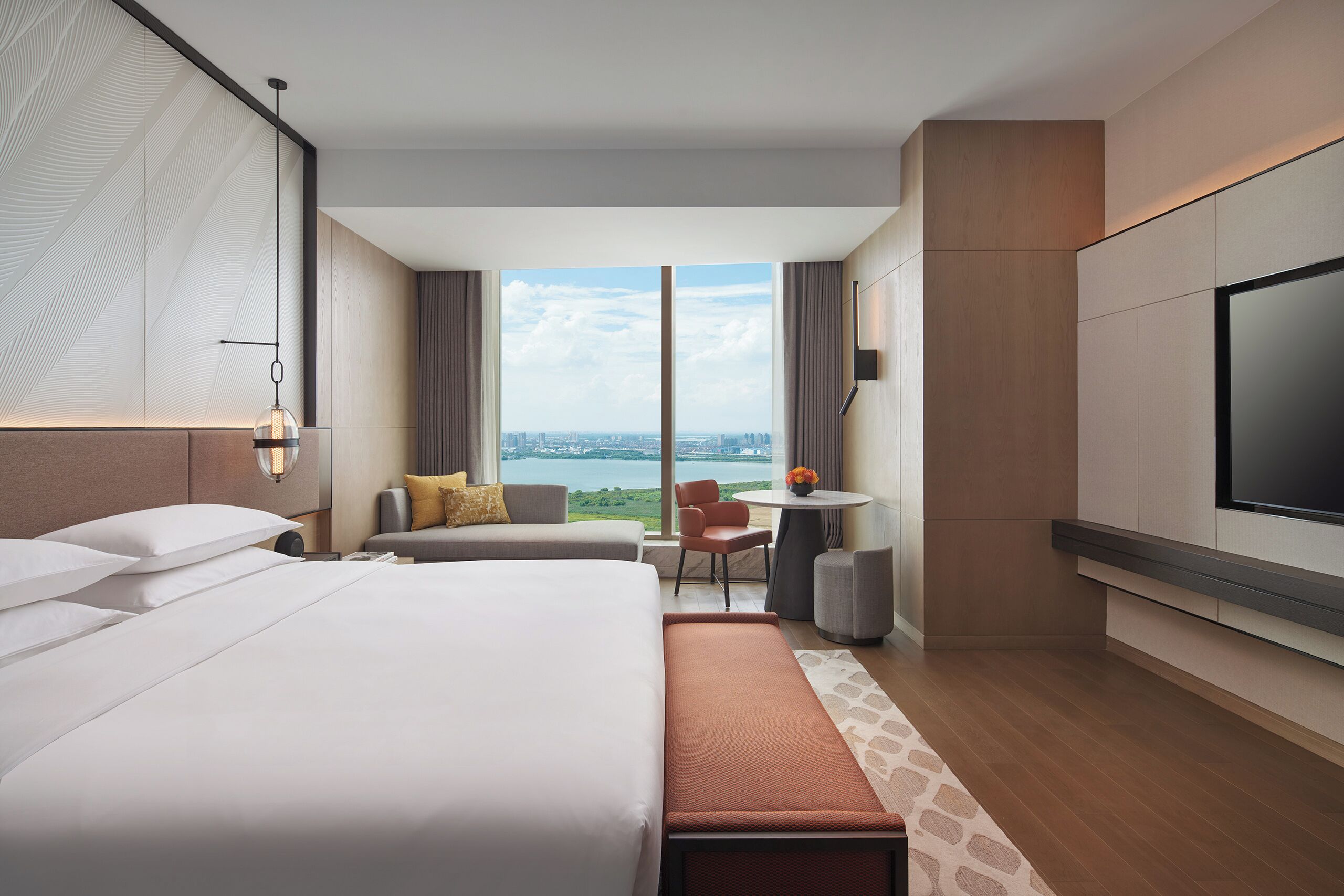 Une chambre d’hôtel avec un grand lit, un bureau, une chaise et un téléviseur.