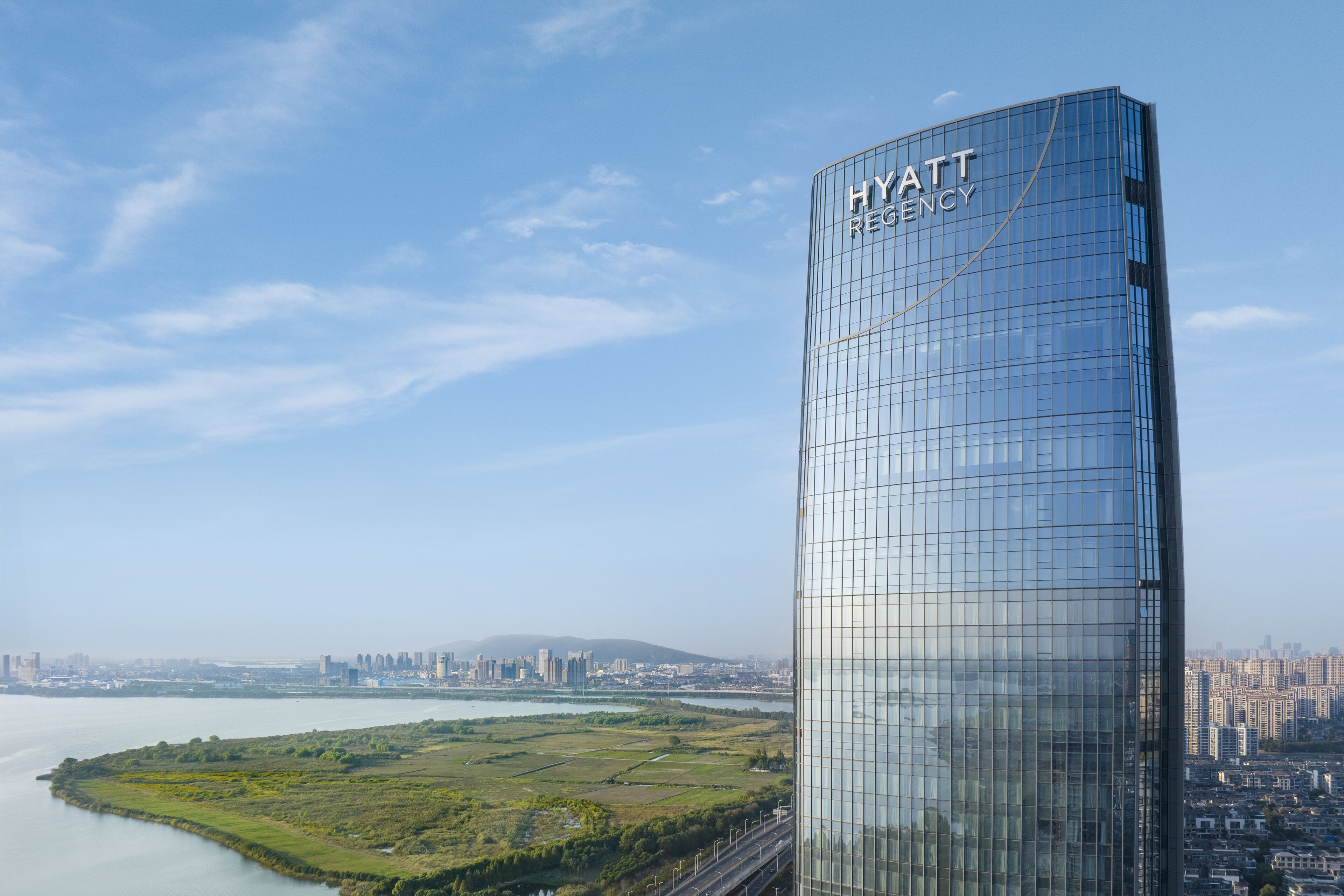 En højhushotel med glasfacade og navnet "HYATT REGENCY" på siden.