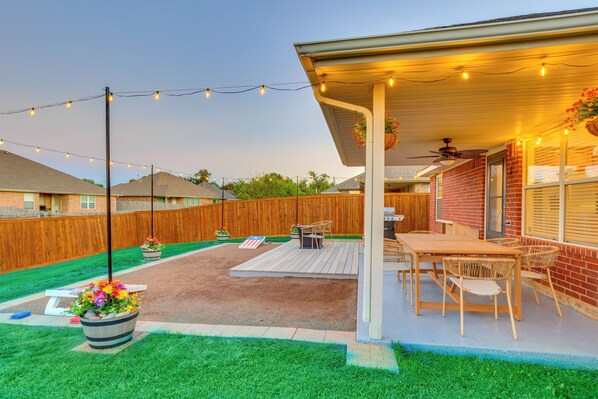 A backyard patio with a wooden deck, outdoor furniture, and string lights.