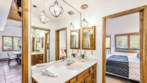 A modern bathroom with a large mirror, wooden cabinets, and a white sink. - 2BR ski-in/out condo in Beaver Creek Village with valley views. (Beaver Creek)