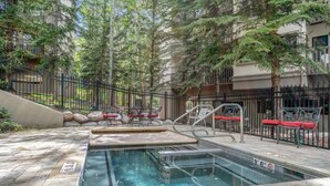 A pool area with a hot tub, lounge chairs, and a staircase leading to a building. - Ski In/out with HOT TUB! PENTHOUSE, Walk to Ski School & Restaurants! BC Village (Beaver Creek)