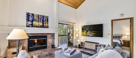 Una sala de estar amplia con chimenea, asientos cómodos, televisor y un ventanal grande.