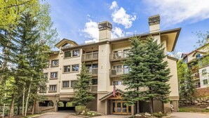 A multi-story hotel with balconies, a central entrance, and a flag. - 2BR ski-in/out condo in Beaver Creek Village with valley views. (Beaver Creek)