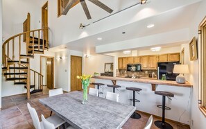 A modern kitchen with wooden cabinets, a central island, and a dining area with a wooden table and chairs.