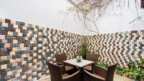 A corner with a mosaic wall, wicker furniture, and a small table with flowers.