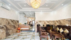 A lobby with marble flooring, a reception desk, and a seating area with a wooden sofa and table.
