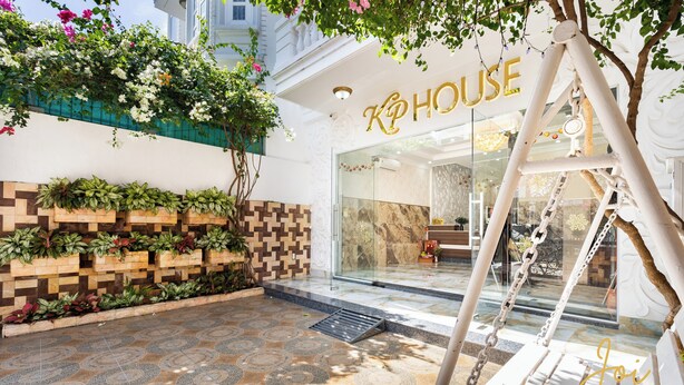 A hotel entrance with a modern design, featuring a swing set, a patterned tile floor, and a planter with green plants.