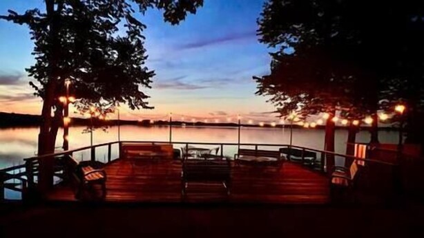 Eine Holterrasse mit Sitzgelegenheiten und Blick auf einen See im Abenddämmerung.
