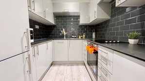 Eine moderne Küche mit weißen Schränken, einer schwarzen Küchenrückwand und einem Holzboden.