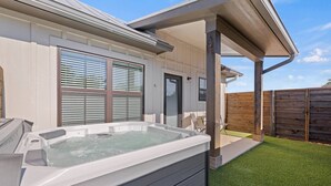 Un espace moderne pour jacuzzi extérieur, doté d’une terrasse en bois, d’un patio couvert et d’une clôture en bois.