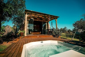 Een hottub op een houten terras, afgedekt door een houten pergola.