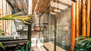 A modern bathroom with a glass shower enclosure, wooden accents, and a stone wall. - Esphera Glamping - Gravataí - RS (Gravatai)
