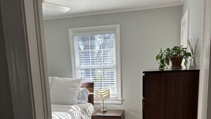 A bedroom with a bed, a nightstand, a dresser, a window with blinds, and a ceiling fan. - Cozy private efficiency located near downtown Raleigh, PNC Arena, NCSU, RTP, RDU (Raleigh)