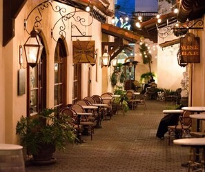 An outdoor cafe area with wicker chairs and tables, a sign for 'Harlocks', and a 'Wine Bar' sign.