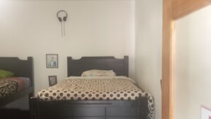 Un dormitorio con una cama litera, una cama individual y una puerta de madera.