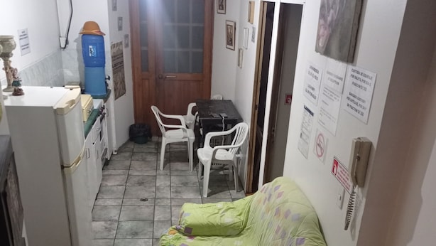 Un espacio habitable pequeño y funcional, con kitchenette, zona de comedor y sofá.