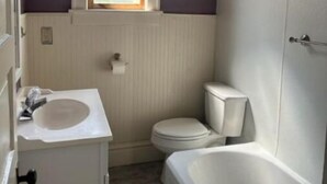 A small bathroom with a window, a toilet, a sink, and a bathtub. - Cozy home away from home.  Located in Steubenville. (Steubenville)