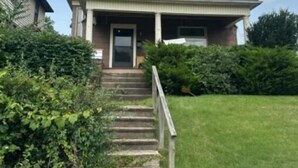 A two-story house with a front porch, a staircase leading to the front door, and a well-maintained lawn. - Cozy home away from home.  Located in Steubenville. (Steubenville)