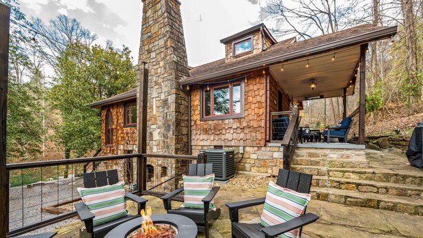 A stone house with a covered outdoor patio, outdoor seating, and a fire pit. - Stone Cabin Retreat - Dog Friendly - Only 1.5mi to town & access to free trolley (Gatlinburg)