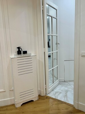 Uma porta branca com painel de vidro, um radiador branco e uma pequena mesa com objetos sobre ela.
