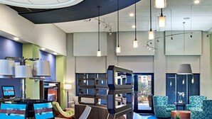 Eine moderne Lobby mit einer gebogenen Rezeption, mehreren Computerarbeitsplätzen, einer Sitzecke mit Sofa und Sesseln sowie einem großen Fenster mit Blick.