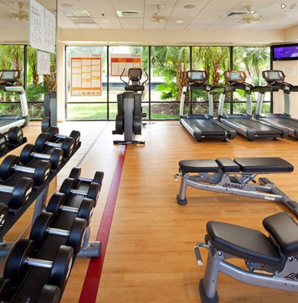 Un gimnasio con cintas de correr, mancuernas y máquinas de pesas.