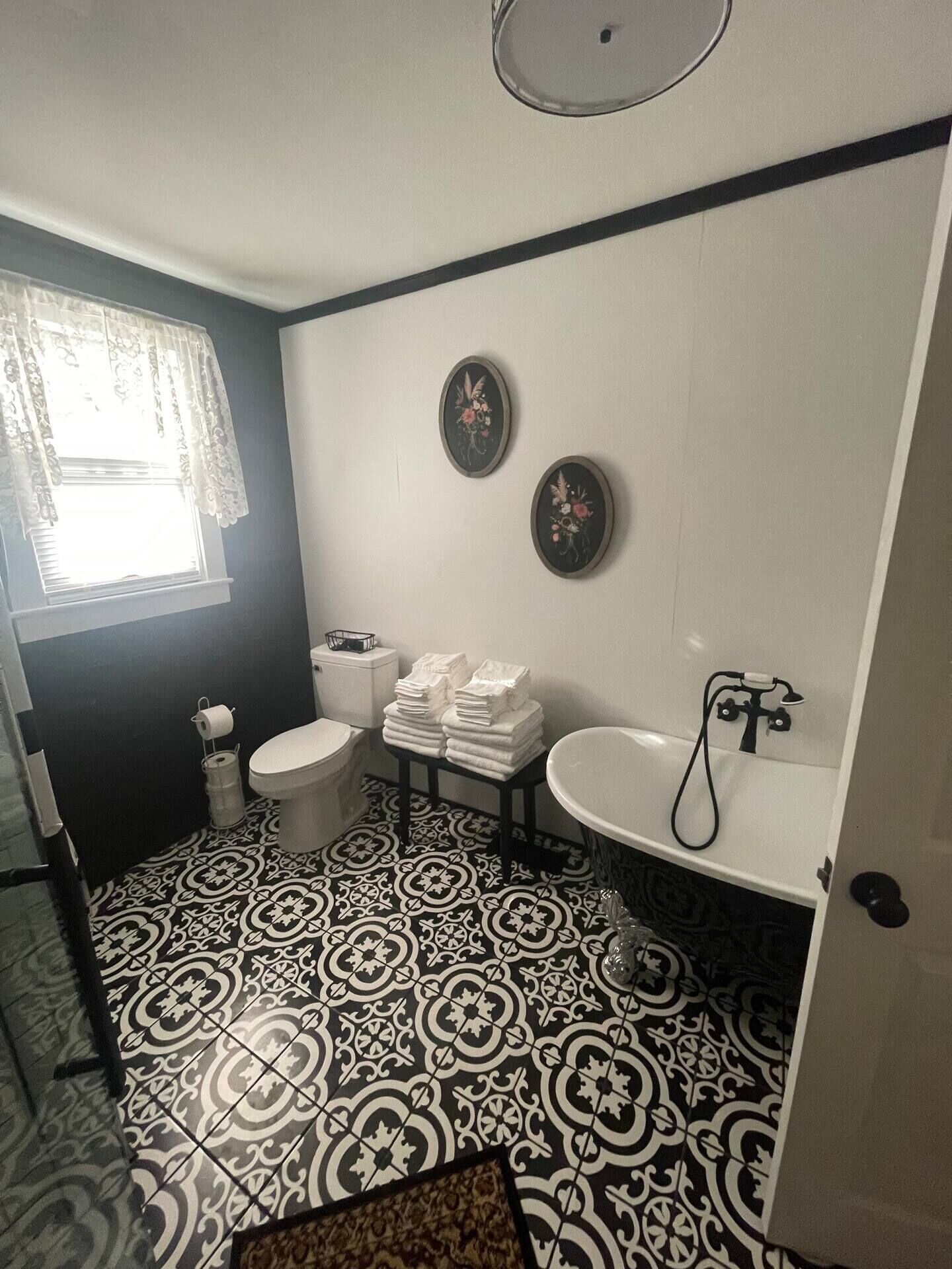 A bathroom with a black and white patterned floor, a toilet, a sink, and two wall-mounted decorative plates.