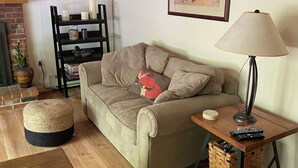 A cozy living room with a sofa, a coffee table, a lamp, and a framed picture on the wall.