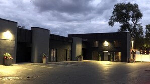 A parking lot with a building entrance, potted plants, and a tree. - Modern Private 2 Room Suite in Boutique Style Hotel - Room #6 (Muskegon)