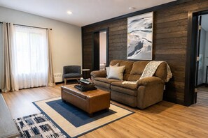 A living room with a brown sofa, a coffee table, and a large abstract painting on the wall.