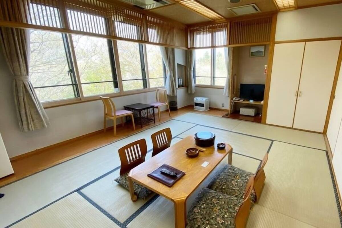 Perinteinen japanilaistyylinen huone, jossa on tatamimatto, matala pöytä tyynyineen ja liukuvat ovet.